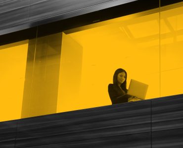 Woman working on laptop, seen through office window