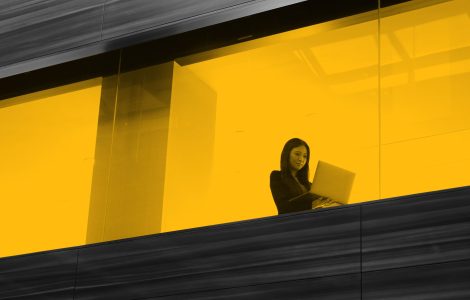 Woman working on laptop, seen through office window