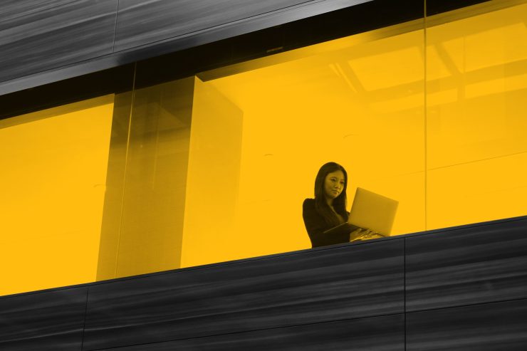 Woman working on laptop, seen through office window